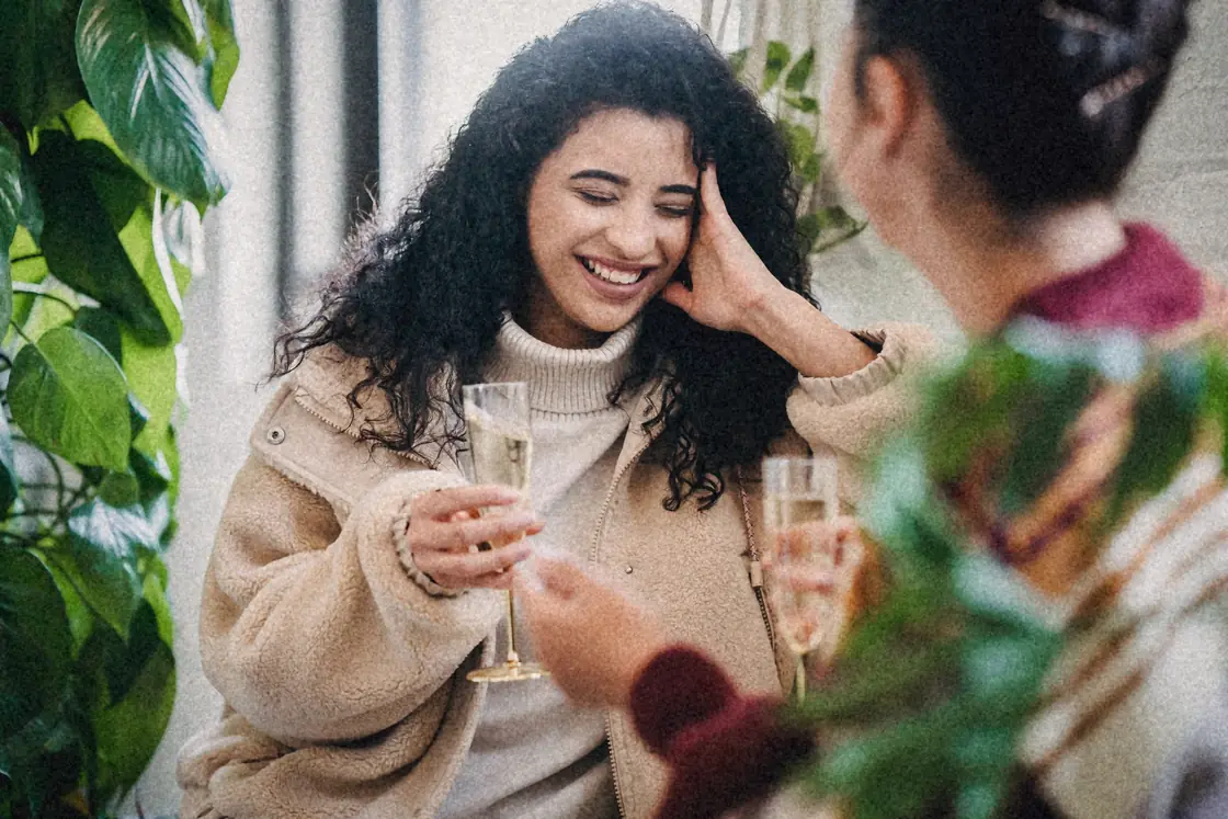 Friends laughing over drinks at home