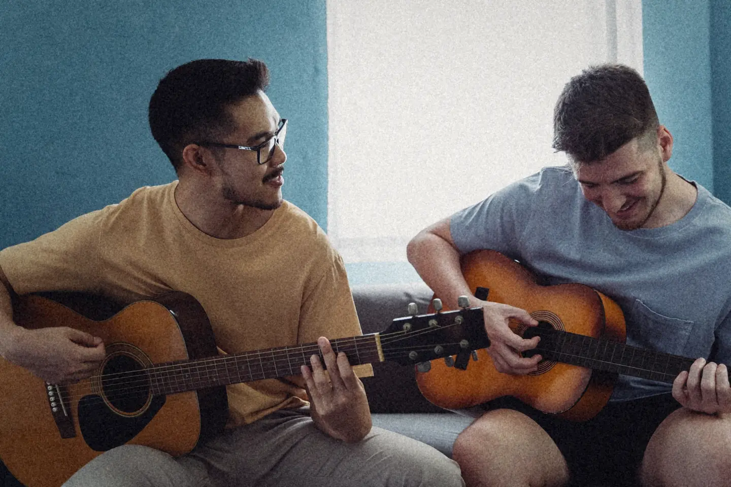 One friend showing another a chord on the guitar